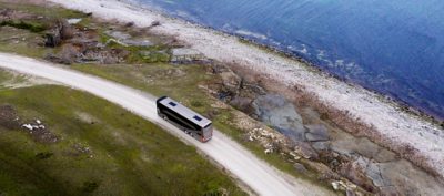 A Volvo 9700 DD viewed from above on a road close to a rocky pebble beach