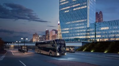 A Volvo 9700 Double Decker leaving a bus stop in a city with lit street lights