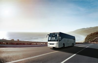 A Volvo 9700 driving on a highway next to the ocean