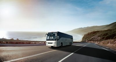 A Volvo 9700 driving on a highway next to the ocean
