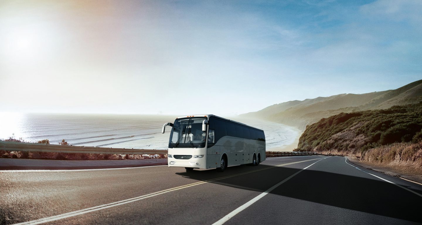 A Volvo 9700 driving on a highway next to the ocean