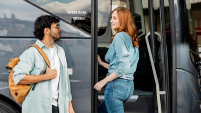 Male and female passengers talking while boarding a Volvo 9800.