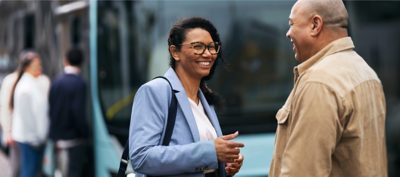 A smiling couple talking at a bus stop