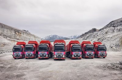 Range of 7 orange volvo autonomous trucks in a quarry