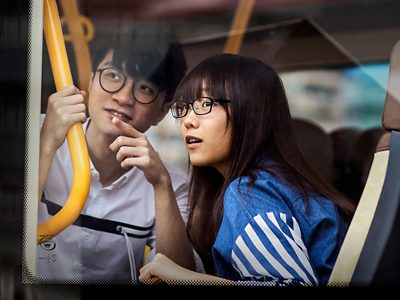 Two passengers on a city bus looking out through the window