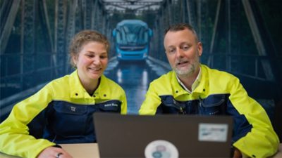 Two Volvo Buses employees collaborating at a laptop, representing teamwork and people-focused sustainability.