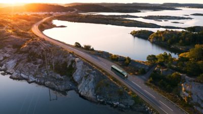 A Volvo BZR Electric coach driving on a road through a coastal landscape
