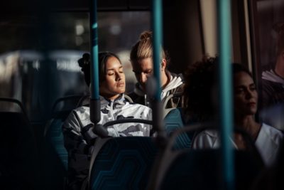 Un jeune couple confortablement installé dans un autobus avec des rayons de soleil qui traversent la fenêtre