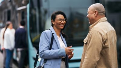 A smiling couple talking at a bus stop