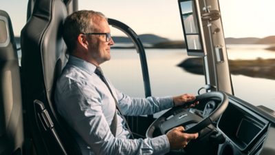 Interior side view of a driver at the steering wheel in an electric Volvo coach