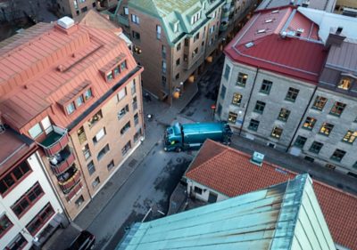 Elektryczny samochód ciężarowy Volvo poruszający się wąską ulicą miasta, ilustrujący, jak ciche, bezemisyjne układy napędowe i inteligentne systemy bezpieczeństwa pomagają operatorom spełniać surowe miejskie przepisy dotyczące emisji, hałasu i prędkości.