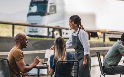 People in cafe environment with a Volvo truck in the background