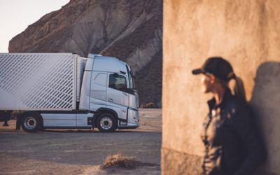 Frau im Sonnenuntergang blickt auf den Volvo FH16