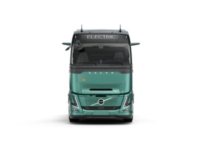 De Volvo FH Aero Electric-truck is van voren gefotografeerd in een strakke studio-omgeving. De turquoise cabine is voorzien van het opschrift "ELECTRIC" boven de voorruit, en de aerodynamische details van de carrosserie zijn duidelijk zichtbaar.