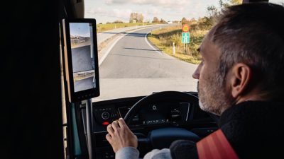 Ein Fahrer steht vor einem Volvo Lkw, während die Sonne hinter ihm untergeht