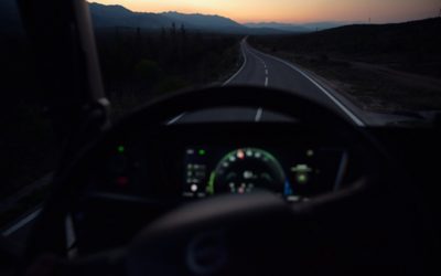 The view from inside a truck, seeing a sunset and a straight road