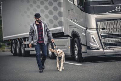 Mann med hund foran Volvo FH