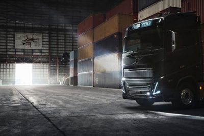 Volvo FH zaparkované mezi kontejnery ve tmavém skladu