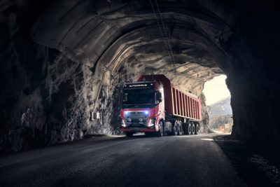 a red Volvo FH truck autonomously driving entering a tunnel in a Norwegian quarry