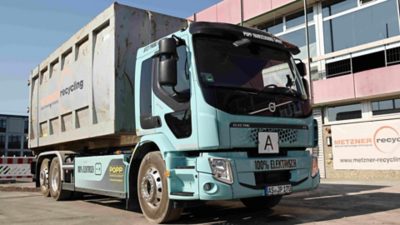 Elektrischer Volvo FE 6x2 Abrollkipper von Metzner Recycling beim Transport von Baumaterialien in Erlangen.