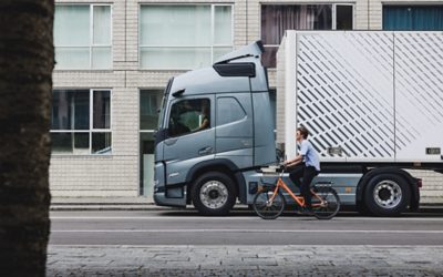 Un biciclist care pedalează lângă Volvo FM