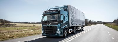 Camião Volvo FM movido a gás a conduzir numa estrada aberta através de uma paisagem rural, demonstrando a sua capacidade de longo curso e um desempenho suave em condições reais.