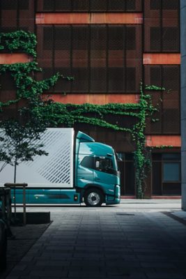 Samochód ciężarowy Volvo FM zaparkowany na spokojnej ulicy miejskiej, prezentujący niskoemisyjny i cichy układ napędowy, zgodny z normami dotyczącymi dostaw miejskich.