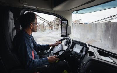 Vīrietis kravas automašīnā ar rokām uz stūres