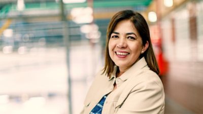 A woman smiling in a workplace environment, representing inclusive hiring and workforce diversity.