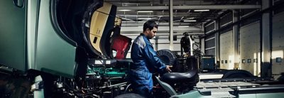 A Volvo service technician works on a part inside a workshop