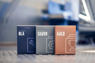 Lådor som representerar Volvos serviceavtal är placerade på en verkstadsyta och visar olika servicenivåer i en verkstadsmiljö.