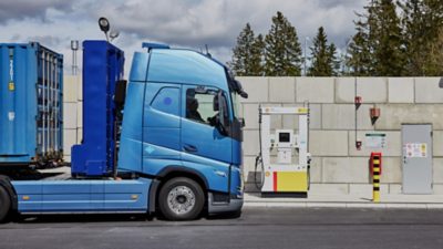 Sideview of  a Volvo FH fuel cell electric truck next to a fuel station