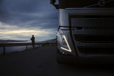 Vrachtwagenchauffeur staat buiten naast zijn Volvo-truck om te pauzeren.