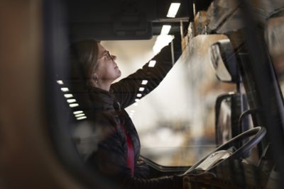 Vrouwelijke vrachtwagenchauffeur bedient de tachograaf in stilstaande Volvo-truck.