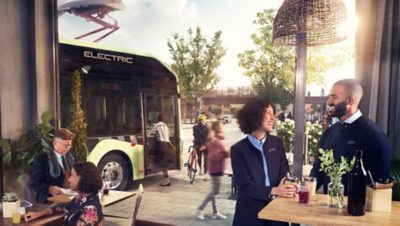 En elektrisk buss ved et busstopp ved en hyggelig kafé hvor bussjåføren tar en pause