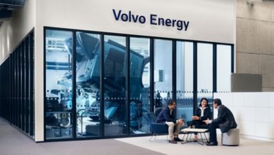 A woman and two men discussing in Volvo Energy's office seating area.