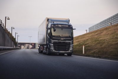 Volvo FH16 driving on dusty road with mountains in background