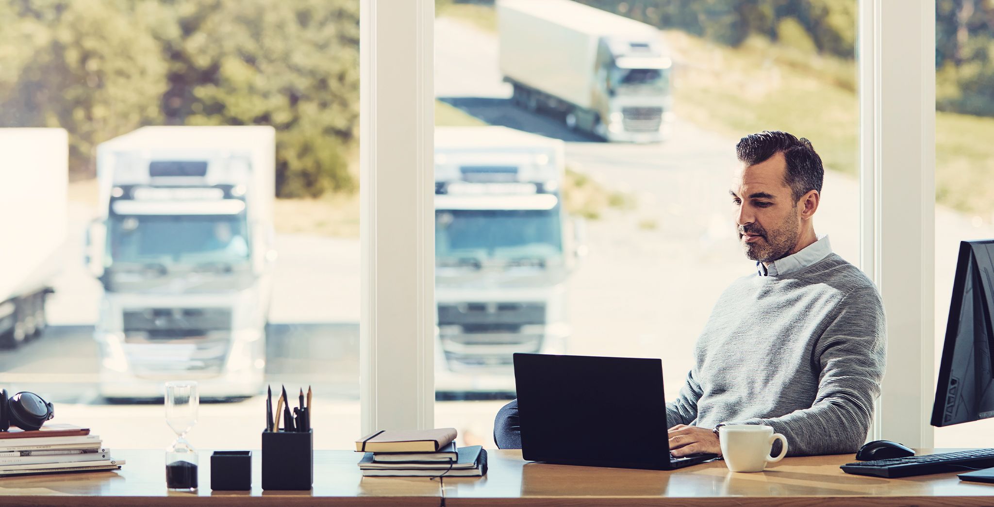 Man zit aan zijn bureau en kijkt naar een computer voor wagenparkbeheer