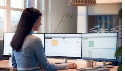 Woman standing with headset on and looking in several screens